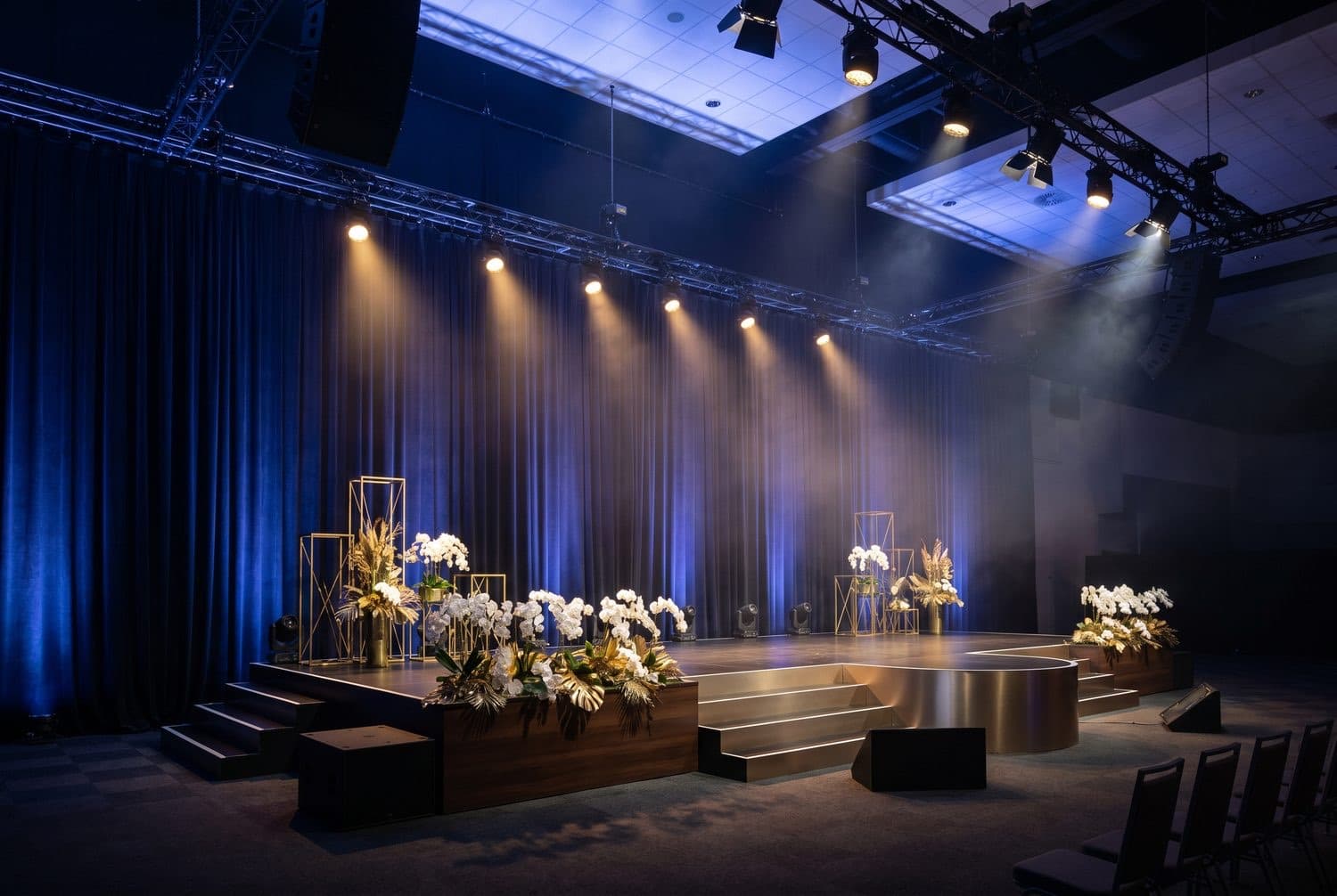 A ceremonial stage under stage lighting, dressed for an official programme